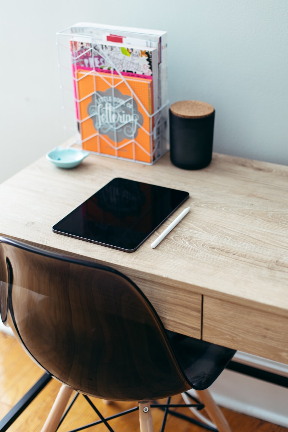 Tablet and stylus on a light wood desk with notebooks.