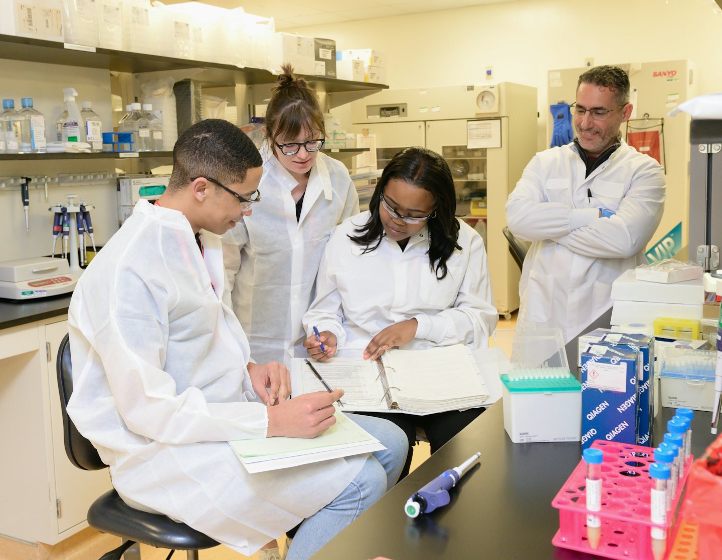 Scientists collaborate on research papers and a laptop in a lab.