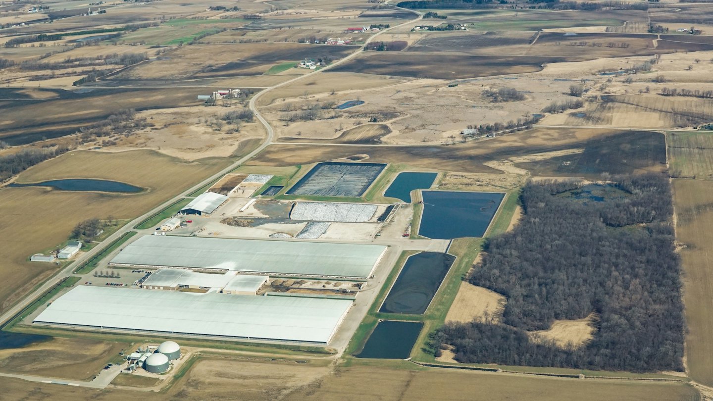 Large agricultural facility with dome structures near rural farmland fields.